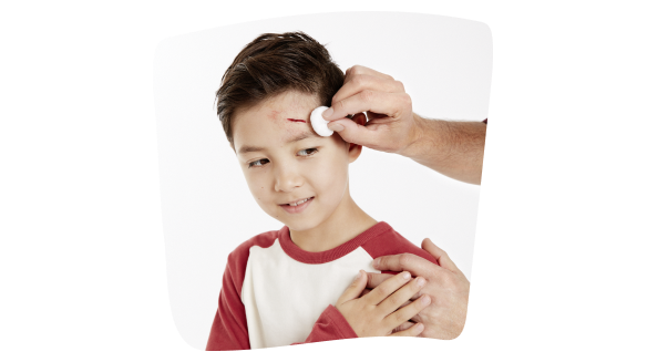 Persona curando una brecha en la cabeza a un niño Persona curando una brecha en la cabeza a un niño